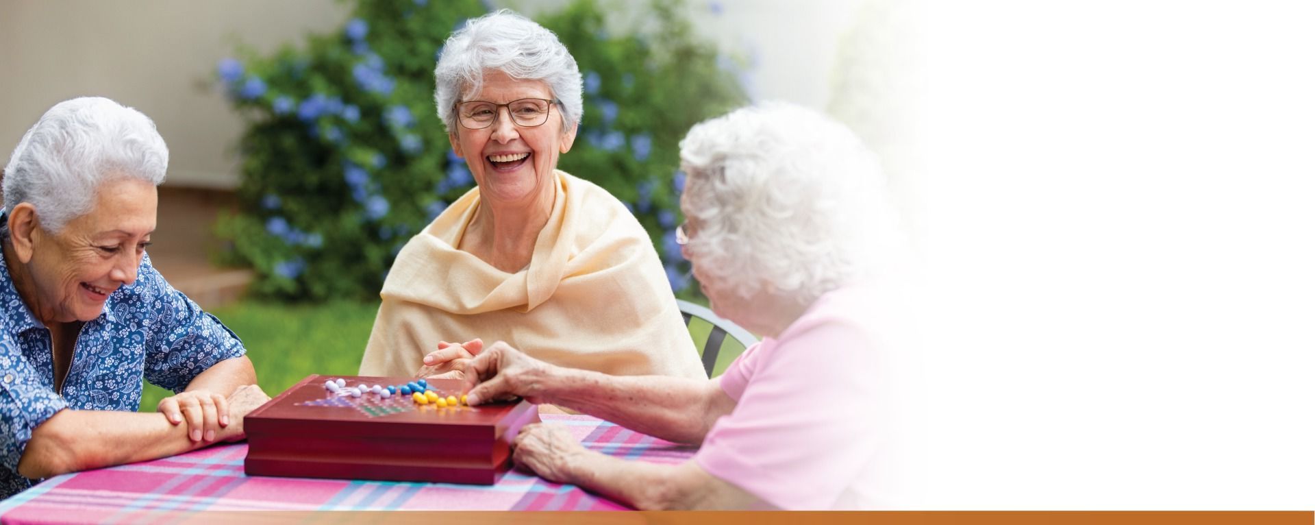 Three senior women playing Chinese checkers in patio