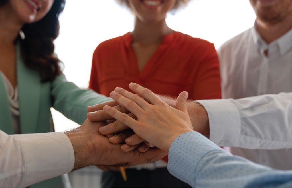 Team members with their hands all in for team work.
