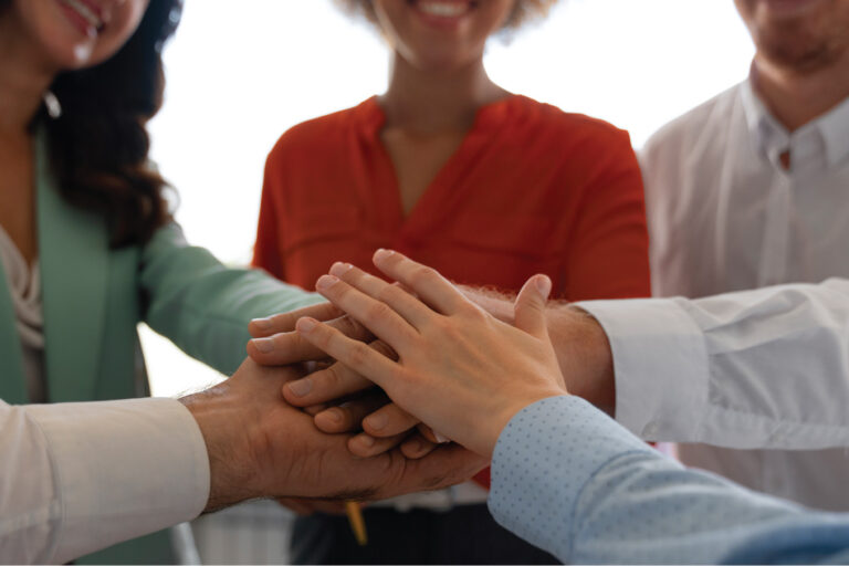 Team members with their hands all in for team work.