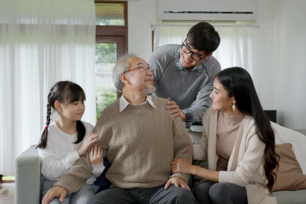 Family members sitting with and comforting senior father