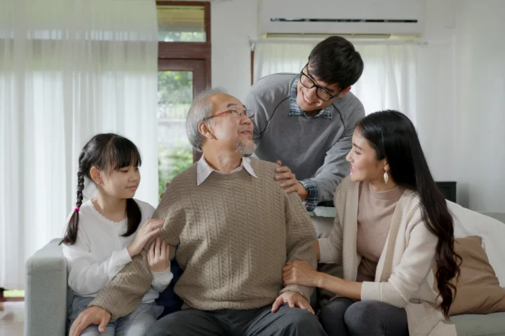 Family members sitting with and comforting senior father